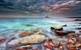 Rocky beach lighthouse mystical colors - a light house in the distance free wallpaper for desktop