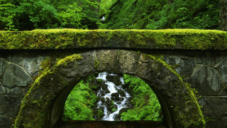 Stone arch waterfall mossy wall - a waterfall in the middle of it free wallpaper