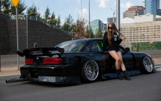 Woman blackcar crossedlegs outdoor cityscape - the hood free wallpaper