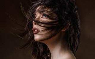 Woman blowing hair blue eyes 5 - a black background behind her free wallpaper