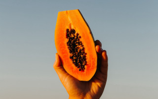 Person holding half papaya sky - a sky background in the background free wallpaper