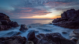 Rocky beach sunset cave city - a sunset in the background and a body of water free wallpaper
