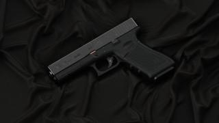 Black gun on wrinkled cloth - a black cloth free wallpaper