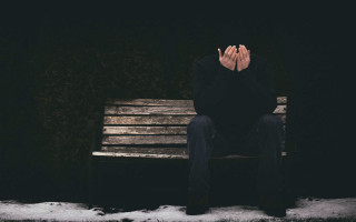 Man sitting bench covering face - somber free wallpaper