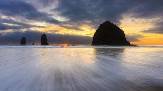 Sunset beach rock formation water 2 - a sunset over a beach free wallpaper