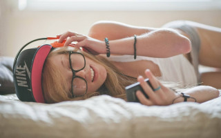 Blonde girl laying bed headphones - her head and a cell phone free wallpaper