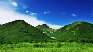 Green mountain range blue sky 5 - a green field in the foreground free wallpaper