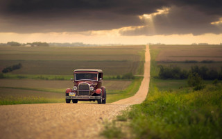 Vintage car dirt road sunset - a sunbeam in the background free wallpaper