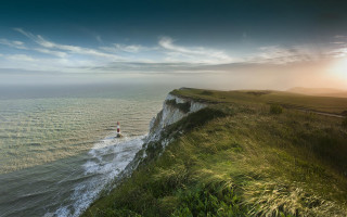 Cliff overlook sunset lighthouse beach - a lighthouse in the distance free wallpaper