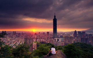 Person sitting rock overlooking city - free city wallpaper