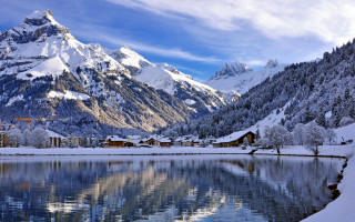 Mountain lake houses snowy sky - mountain in the background free wallpaper