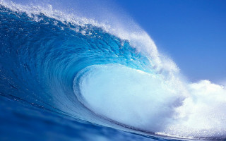 Large blue wave breaking ocean - a blue sky in the foreground free wallpaper
