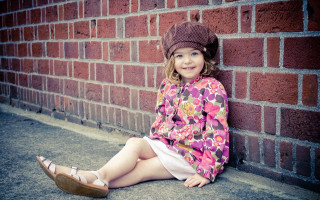 Little girl brick wall smiling 2 - the ground next free wallpaper