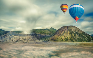 Two hot air balloons over - over a mountain range in the sky free wallpaper