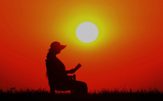 Woman sitting reading sunset silhouette - the sun setting behind her free wallpaper for desktop