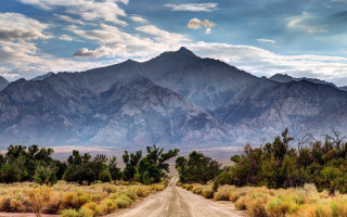 Mountain road clouds bushes sky 2 - a dirt road in front free wallpaper