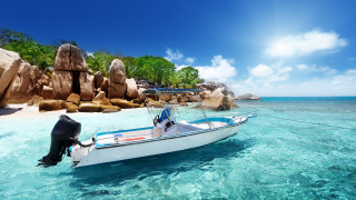 Docked boat rocky shore beach - a rock formation in the background free wallpaper