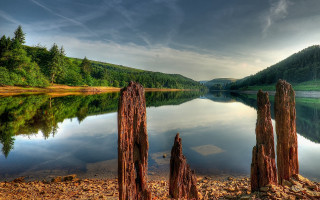 Lake trees rocks cloudy mountain - under a cloudy sky free wallpaper