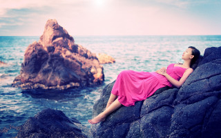 Pink dress woman laying rock - a rock formation in the background free wallpaper