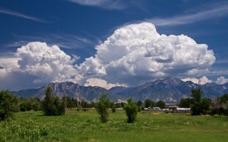 Mountain field trees clouds sky - a mountain range in the background free wallpaper
