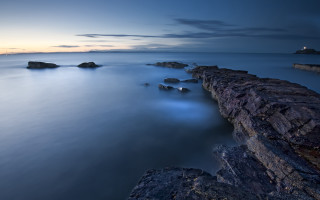 Lighthouse rocks water mountains clouds - rich moody colour free wallpaper