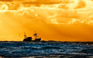 Boat ocean yellow sky clouds 2 - a boat in the ocean free wallpaper