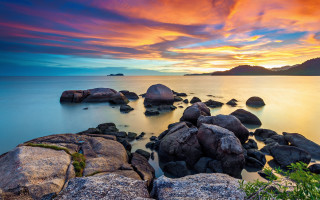 Sunset rocky beach mountain clouds - the water and a mountain in the distance free wallpaper