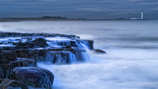 Lighthouse waves rocks beach cloudy - against the rock free wallpaper