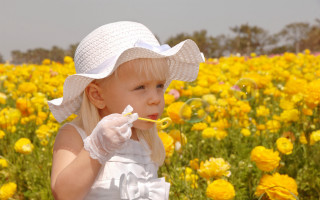 Little girl blowing bubbles yellow - a gray sky in the background free wallpaper