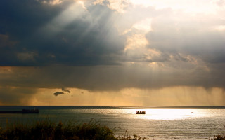 Boat sunset mountain ocean godrays - the water under a cloudy sky free wallpaper