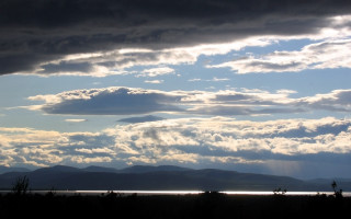 Stormy water mountains cloudy sky - a large body of water under a cloudy sky free wallpaper