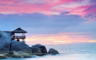 Small hut rock ocean sunset - a pink sky in the background free wallpaper