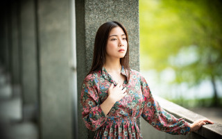 Woman leaning wall serious portrait 3 - the side with free wallpaper