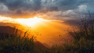 Sunset mountain range grass field - a sunset over a mountain range free wallpaper