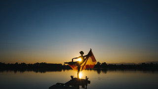 Dusk sunset flag person dock - the sun setting behind them free wallpaper