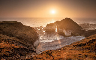 Sunset ocean rocky outcropping beach - dramatic light free wallpaper