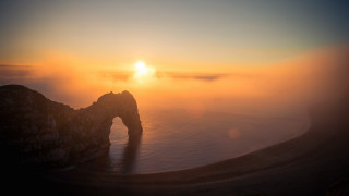 Sunset foggy mountain arch volumetric - a bright sun in the distance free wallpaper