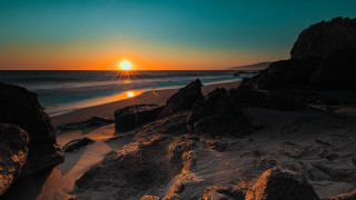 Sunset ocean beach rocks sand - the beach in the distance free wallpaper