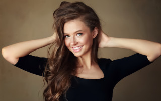 Woman smiling longhair holding hair - both hand free wallpaper