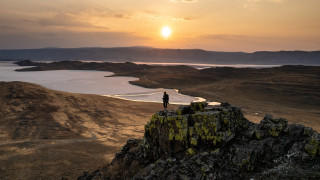Person rock overlooking lake mountains - over the water free wallpaper