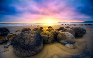 Rocks sandy beach cloudy sunset - a sandy beach under a cloudy sky free wallpaper
