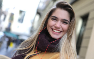 Blonde woman scarf headphones smile - a city street in the background free wallpaper