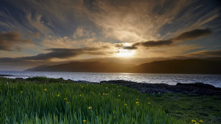 Sunset grass field mountains lake - a sunset in the background and a body of water free wallpaper