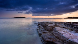 Rocky shore lake island cloudy - free sunset wallpaper