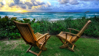 Wooden chairs lush green ocean - the ocean under a cloudy sky free wallpaper