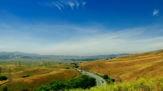 Scenic hills road blue sky - a green field below free wallpaper for desktop