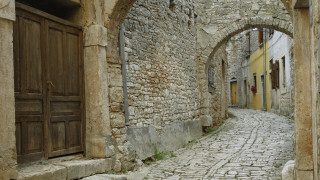 Narrow cobblestone street romanque arch - a stone building free wallpaper