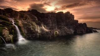 Waterfall over ocean sunset mountain - a sunset in the background free wallpaper for desktop