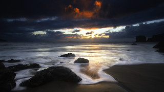 Sunset ocean rocks cloudy sky 4 - a dark sky in the background free wallpaper