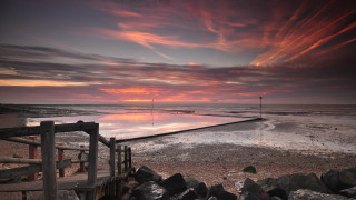 Sunset beach fence water cityscape - rich moody colour free wallpaper